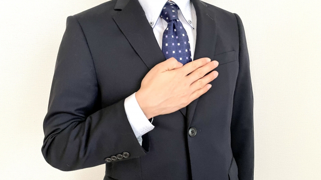 A man in a suit putting his hand on his chest