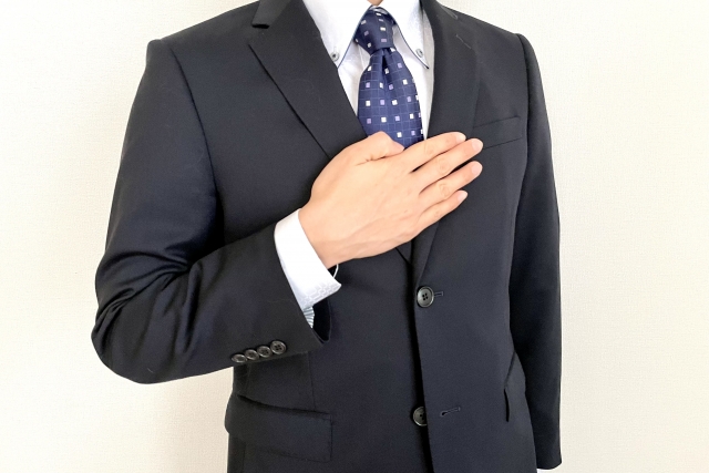 A man in a suit putting his hand on his chest